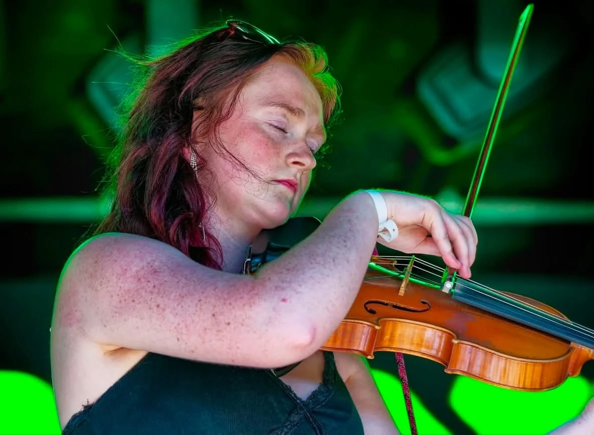 The fiddle player performing under green stage lights